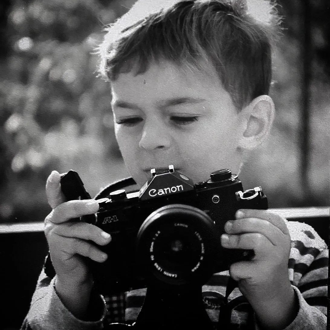 Young Mike Mala age 5 holding a Canon A-1 35mm film camera — a lifelong passion for photography